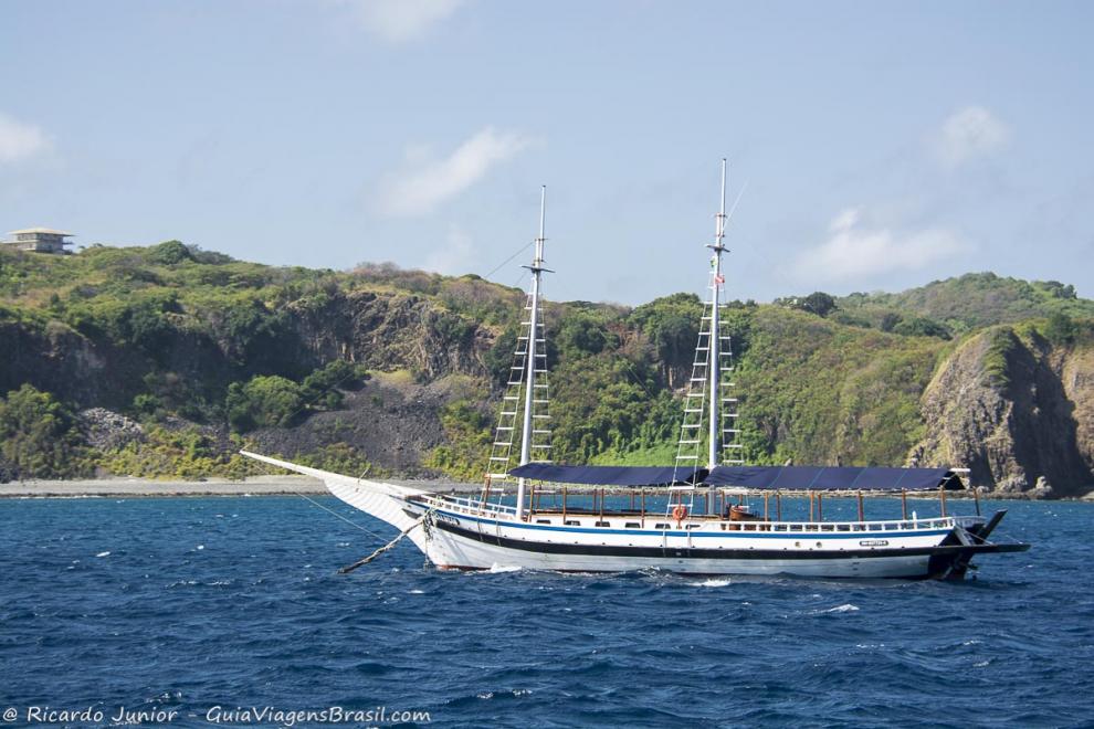 Imagem de lindo barco de passeio e ao fundo morro.